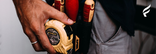 An image of a person holding a tape measure on a toolbelt