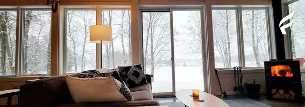 Image of a cozy living room with a wood burning stove on a snowy day.