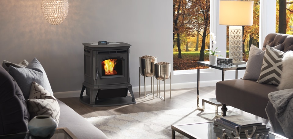 A cozy living room features a lit pellet stove and elegant pendant lights, surrounded by sofas and decorative lamps.