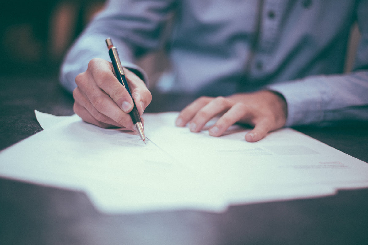 image of hands holding pen filling out tax forms